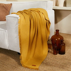 Marceau throw in mustard yellow on a sofa - Bercail